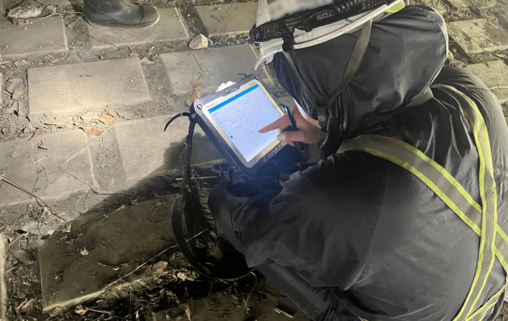 現場でタブレットを操作しながら点検を行う作業員